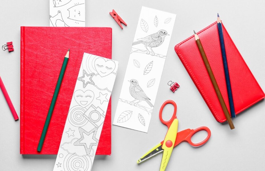 Picture of notebook and scissors and some coloring in bookmarks and a pencil and some paper clips. Part of an article - decorate your planner with these 10 creative ideas