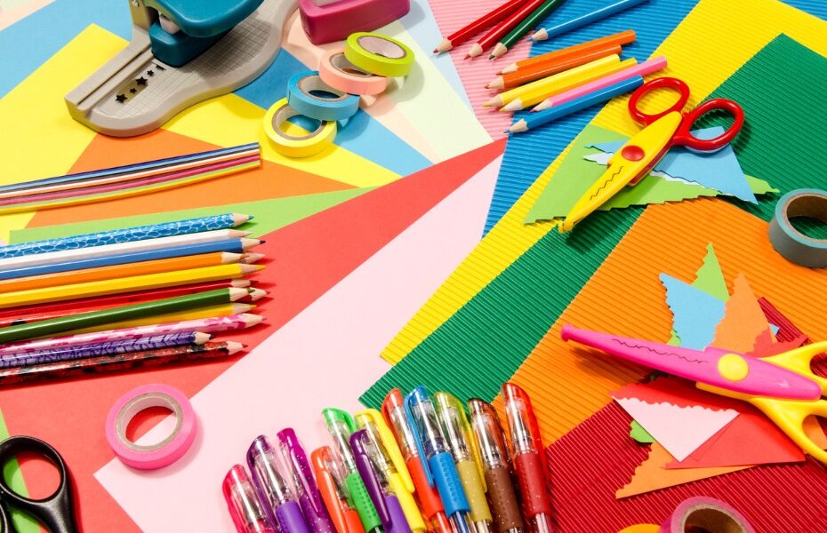 Picture of laid out paper craft tools and colored paper on a table. Part of an article - Affordable planning: the cost of making a planner