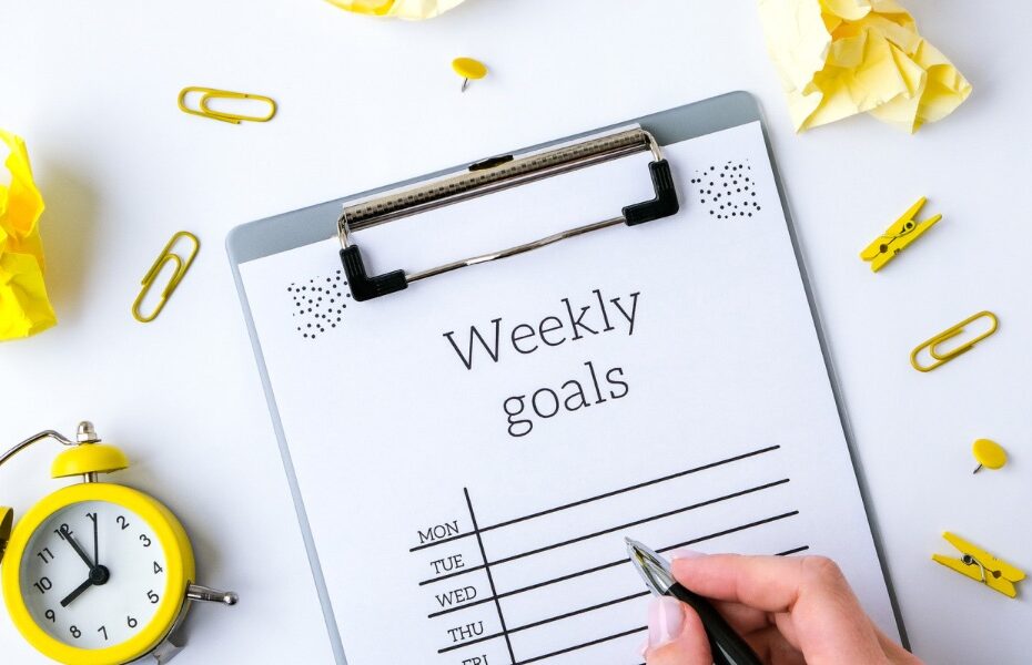 Picture of a weekly goals planner page that is surrounded by paper clips and stationery. Part of an article - are printable planners worth it