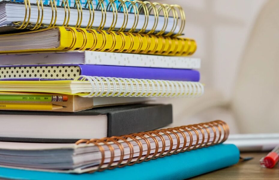Picture of a stack of notebooks in different colors and with different binding. Part of an article: The Search is Over: Finding the Best Bullet Journal Notebook